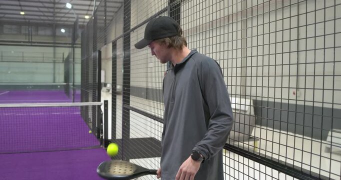 Spotting tethered ball, male athlete practicing drill and tapping it on padel court, copy space
