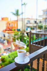 Obraz premium Cup of coffee on a hotel balcony overlooking a swimming pool and tropical courtyard in Tenerife, Canary Islands, Spain.