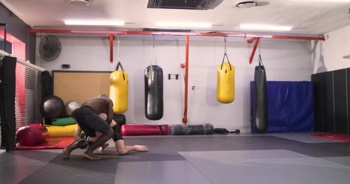 Diverse male fighters entering mat, striking and feinting, hip throwing opponent into mount