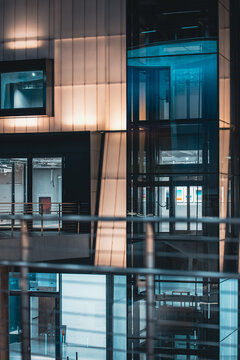 Modern glass elevator shaft with transparent structure and illuminated interior design, Contemporary lift system inside building with reflective surfaces and geometric architecture