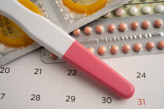 Pregnancy test and birth control pills on calendar, contraception health and medicine.