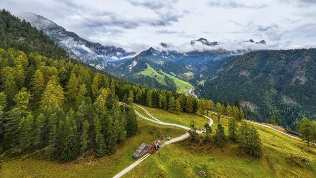 Forest work on the alpine meadow Wuhnleger, in the background the peaks of the rose garden, shrouded in fog, drone shot, Dolomites, Autonomous Province of Bolzano, South Tyrol, Italy