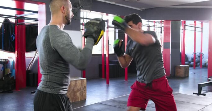 Personal trainer positioning focus pads, indian trainee throwing jab-cross-hook combo drill