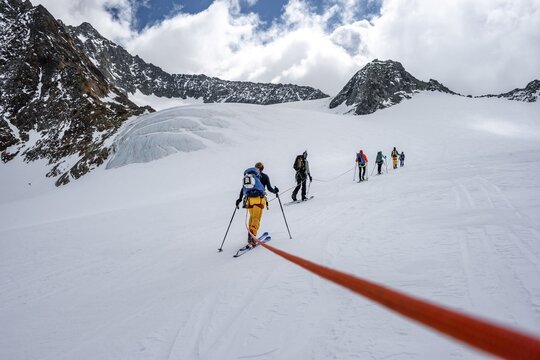 High altitude tour, ski tourers walking on a rope over Alpeiner Ferner glacier, winter in the mountains, Neustift im Stubai Valley, Tyrol, Austria