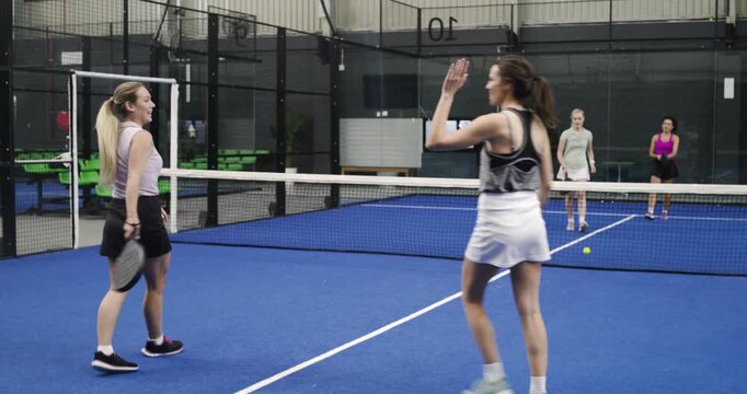 friends reacting to serve and volleying ball on blue padel court for friendly match