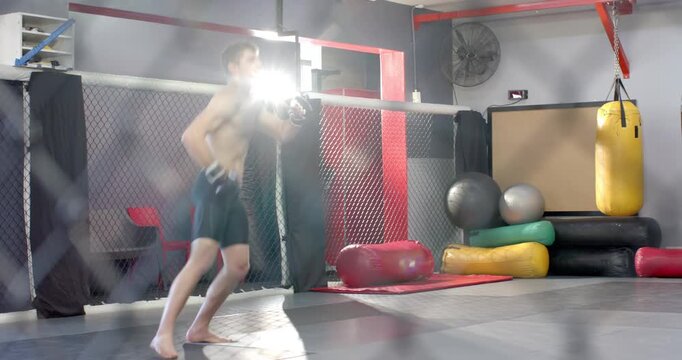 Entering MMA cage, diverse male fighters shadowboxing sparring with gloves on mats for training