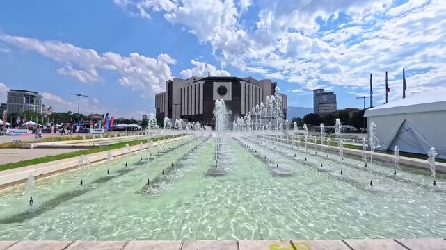 Sofia, Bulgaria - 06.06.2026. Wide panoramic view of fountains in front of the National Palace of Culture NDK, central square in summer daylight. Blue sky with white clouds, clear water, iconic urban
