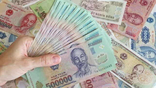 Top view of woman's hand holding big fan stack of 500000 Vietnamese dong money bills. Concept of financial wealth, successful business profit calculation, high income and cash expenses in Vietnam.
