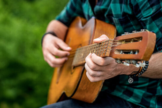 Man 's hand playing acoustic guitar, song. Nature background. Guitars acoustic. Male musician playing guitar, music instrument. Man's hands playing acoustic guitar