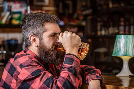 Man with beer. Bearded hipster holds glass of beer. Beer pub. Stylish guy at cafe pub. Beer time. Man drinks beers at the bar counter. People, lifestyle, recreation
