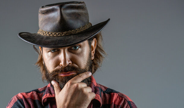 Cowboy hat. Handsome young man adjusting his cowboy hat. Man unshaven cowboys. American cowboy