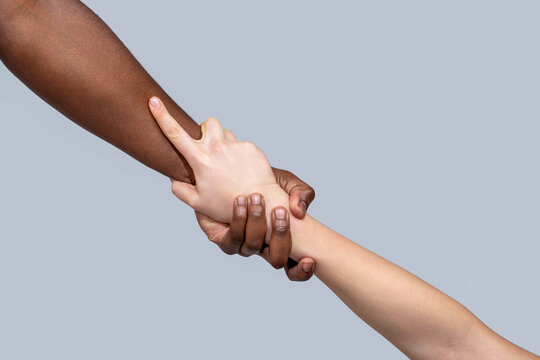 One caucasian and one african hand. Woman and african woman hand. Helping hand, rescue. Interracial forearm shake, helping , humanity and brotherhood concept, helping hands, rescue gesture