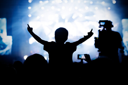 Silhouette of Child on Shoulders Cheering at Music Festival