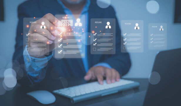 A human resources manager in a business suit reviews floating digital resumes at a workspace.