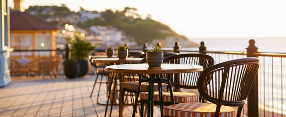 Fototapeta premium Coastal town view from a charming bistro terrace featuring elegant seating and sunlit ocean scenery.