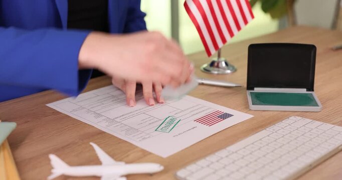 Woman visa center employee places official approval stamp on passport. Female specialist enters application information into database via computer