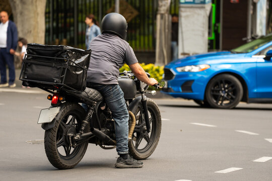 Man riding a motorcycle through a town street, representing urban mobility, freedom, speed, adventure, and modern transportation in everyday city life.