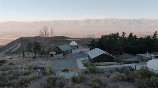 Drone passing above the Ampimpa Astronomical Observatory surrounded by mountain landscapes in Taf&iacute; del Valle, Argentina.