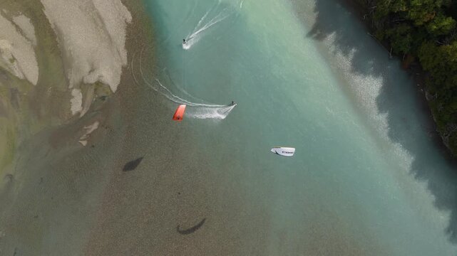 Kitesurfers riding the braided channels of R&iacute;o de las Vueltas near El Chalt&eacute;n, Santa Cruz, Argentina, turquoise glacial waters, kite shadows and sweeping wakes across the river, top down tracking