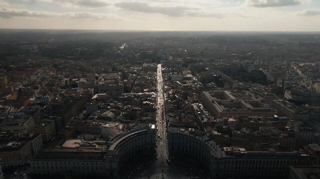 Drone aerial shot flying over Rome's Piazza della Repubblica, showcasing Via Nazionale traffic and the ancient Baths of Diocletian with the historic cloister courtyard.