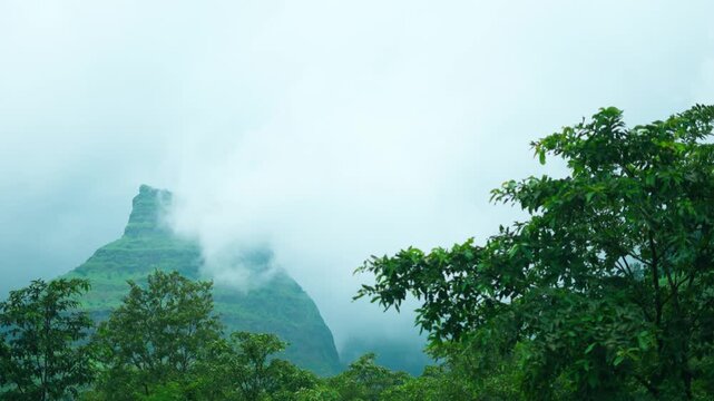 4K Landscape shot of clouds surrounding the green Sahyadri hills during the monsoon season as seen from Maharashtra, India. Scenic view of Western Ghats during the rain. Natural monsoon background.