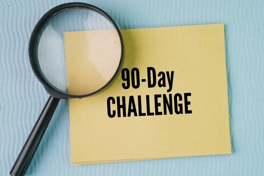 A magnifying glass and paper with the words 90-Day Challenge. structured personal development or habit-building framework that requires you to commit to specific goals for 90 days