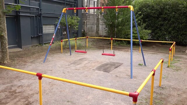 Wide view of empty red swings in a small Japanese urban park