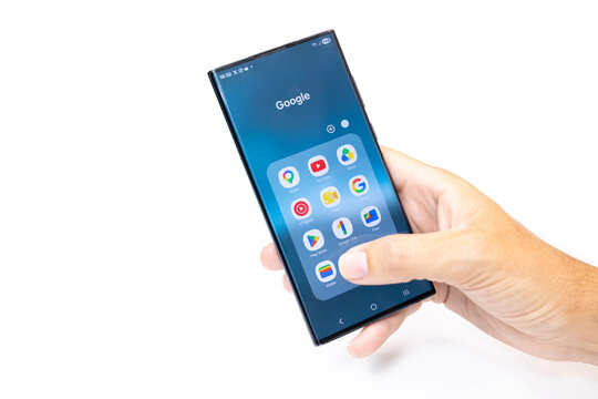 Hand holding smartphone showing google apps interface