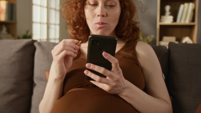 Close up on pregnant Caucasian young adult woman with glucose monitor on arm eating snack and using smartphone. Clip perfect for gestational diabetes care and digital health app marketing