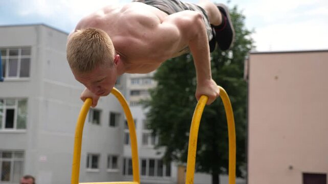Sportsman performing dynamic workout routine on parallel bars, showcasing strength and control through fluid motion, emphasizing athleticism and dedication in outdoor training environment