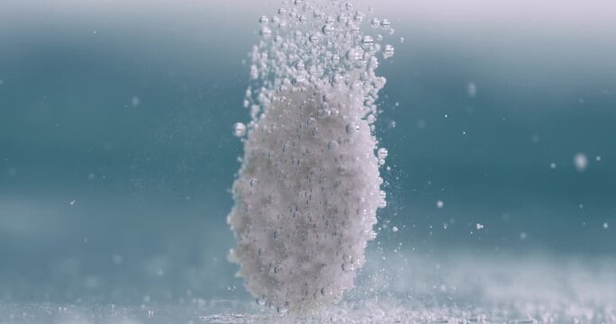 Effervescent tablet dissolving in water creating fizzy gas bubbles for chemical reaction study.