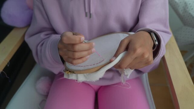 Woman meticulously embroidery with smartwatch on wrist at home