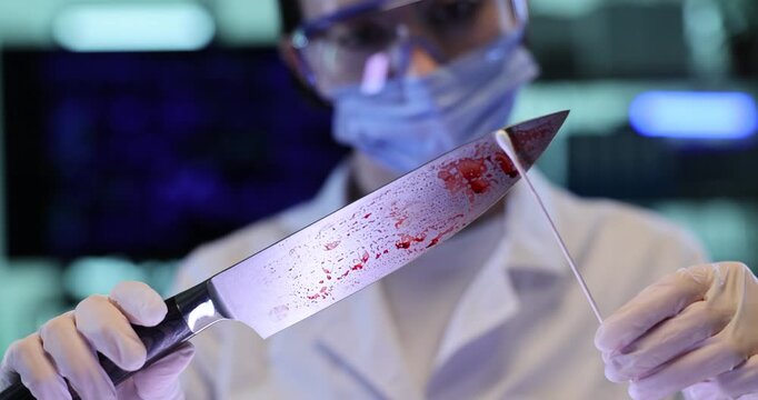 Female assistant takes blood sample from knife with swab in lab. Criminal investigation scientist processes evidence in police laboratory
