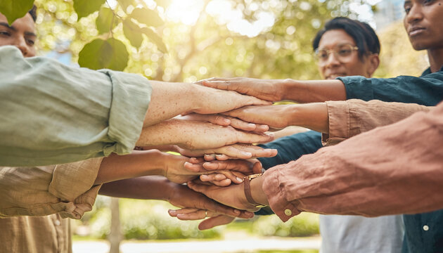 A diverse group of friends stack hands together in a sunny park, symbolizing unity, team collaboration, and strong partnership. Inspiring concept of mutual support and trust.