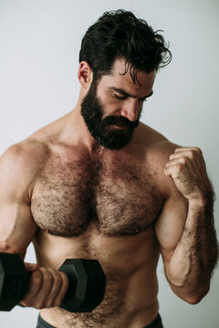 A man of average build and fitness, lifting a black dumbbell in his hand against a plain white background.