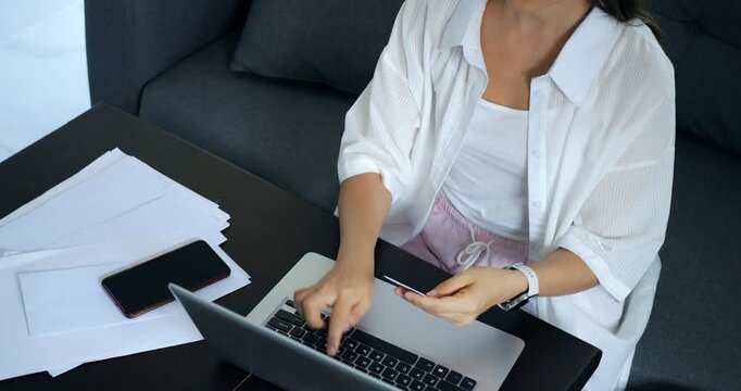 Woman on gadgets. Female working with multiple devices. Woman checking notifications on her electronic gadgets. Lady reviewing alerts on her phone while using her laptop and papers