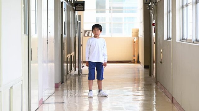 光の差し込む学校の廊下で元気に踊る男子小学生