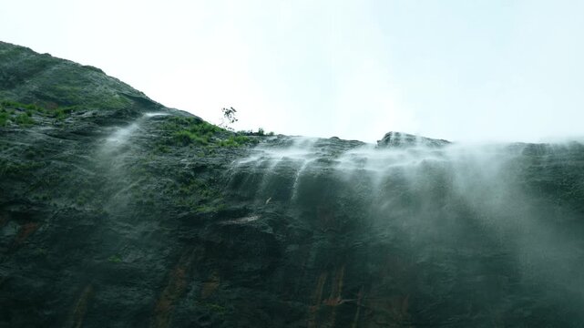 4K slow motion shot of waterfall falling from a cliff as seen while standing directly below it during the monsoon season in the Sahyadri mountain ranges at Maharashtra, India. Scenic view of waterfall