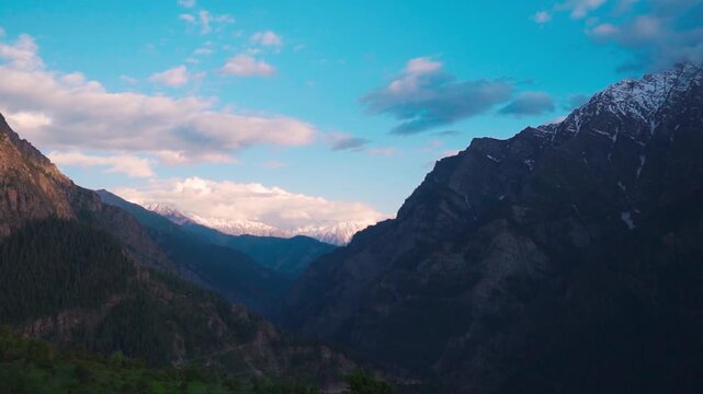 Wide angle shot of scenic mountain valley with snowy Himalayan mountain peaks covered by clouds during evening as seen from Killar town in Chamba district, Himachal Pradesh, India. Natural background