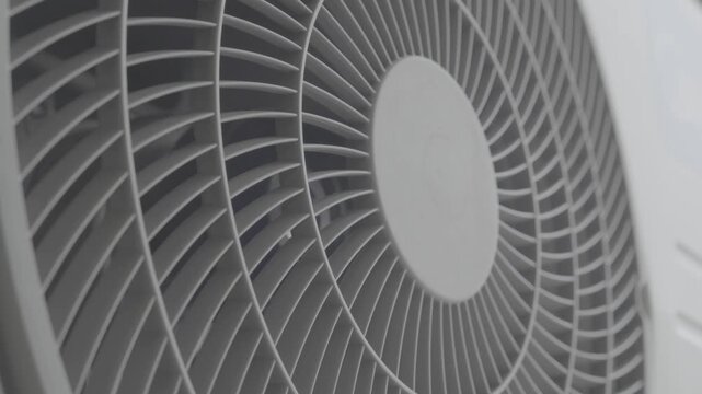 Close up view of an outdoor air conditioner unit with its fan spinning at high speed