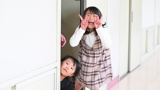 教室のドアから廊下へ笑顔で元気よく飛び出してくる女子小学生たち