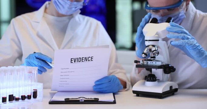 Scientist checks evidences list as colleague looks in microscope in lab. Female forensic experts conduct research for crime scene investigation