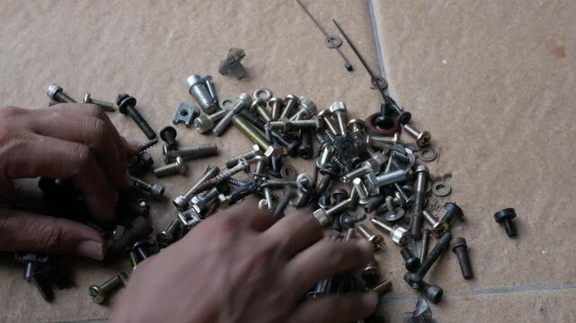 Pouring Mixed Screws, Bolts and Nuts onto Floor from Plastic Container