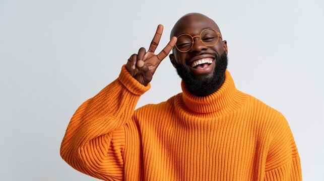 Smiling bearded man in bright orange turtleneck flashing peace sign for cheerful profile banner and social media portrait