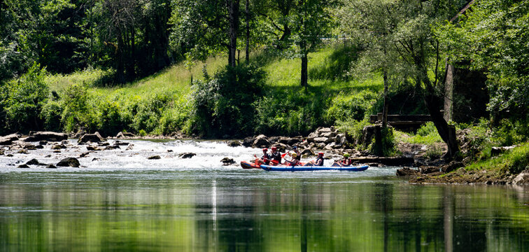 White water rafting activity on the Kolpa River surrounded by lush forest promoting active ecotourism adventure travel and teamwork experiences