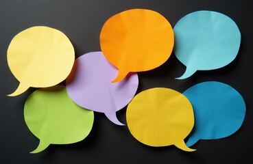 Obraz premium Colorful paper speech bubbles overlap on dark background. Set of empty message icons for communication ideas. Diverse chat symbols for sharing thoughts and opinions.