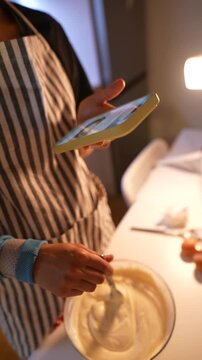 Individual carefully following electronic recipe while preparing batter