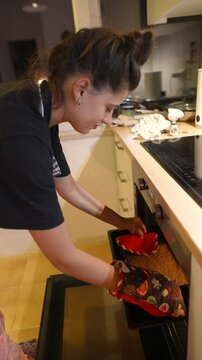 Young woman places tray in oven during evening baking session
