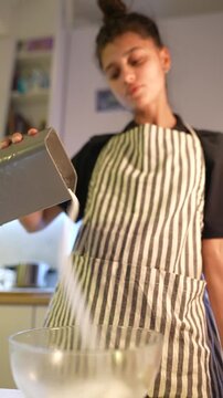 Young woman measuring. She measures ingredients with focused attention