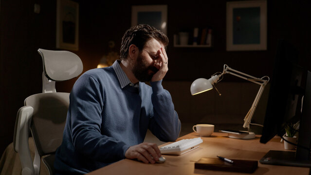 Facepalm. Frustrated man at computer covered his face with his hand